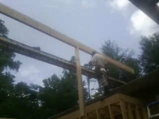 Carpenter setting a ridge beam over a new addition frame — Ice Dam Removal by Roofing Brothers in West Mansfield
