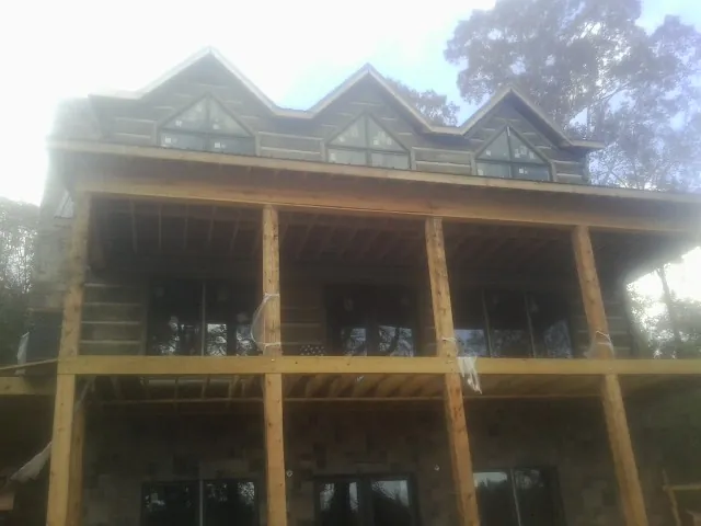 Dormers and porch framing on a large log home under construction — Roof Coating work by our crew in West Mansfield