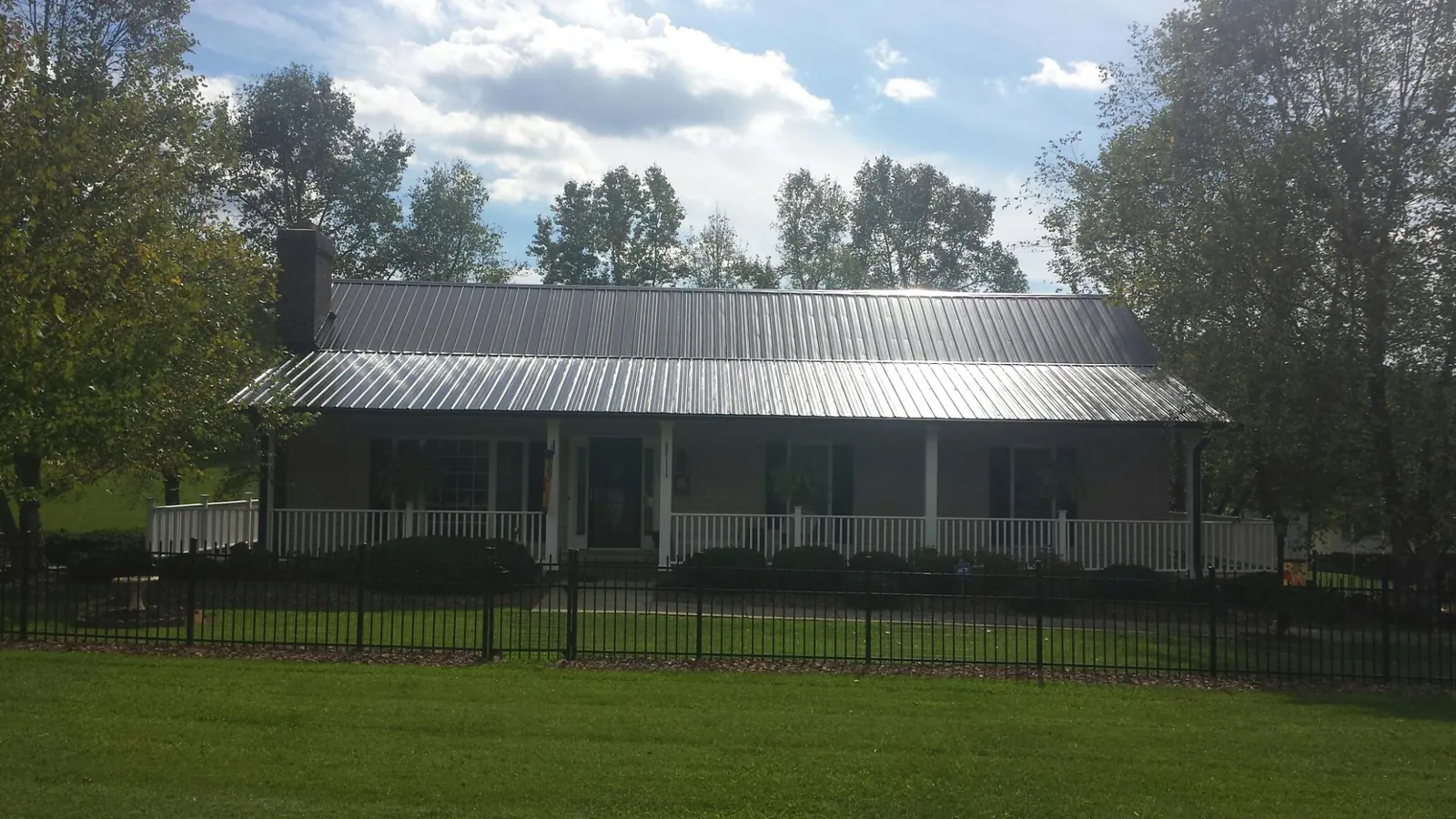 Gray metal roof on a brick ranch with a full width front porch — Gutter Guard Installation work by our crew in West Mansfield