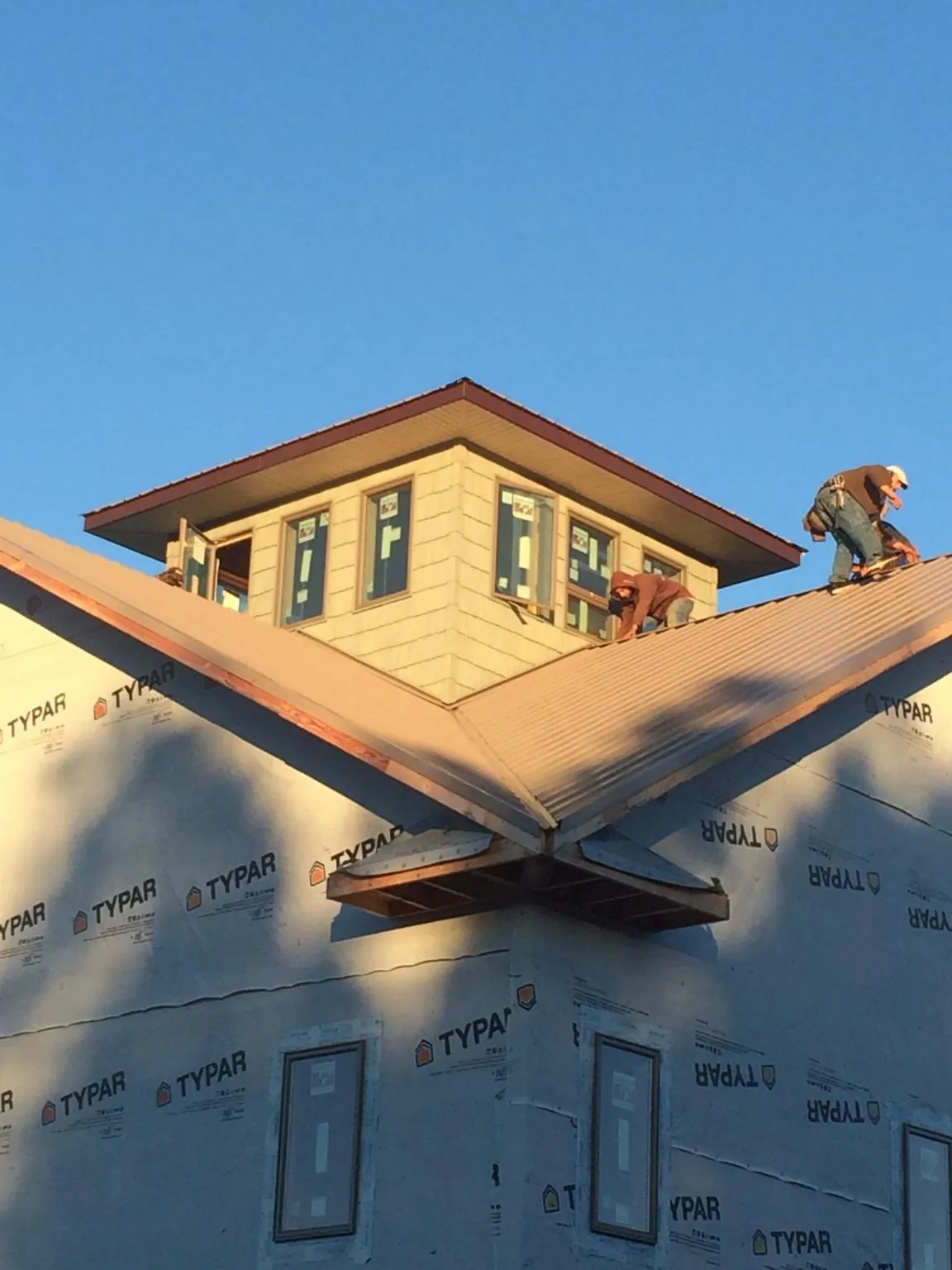 Roofers working around a rooftop cupola on a new metal roof at sunset — Roof Waterproofing in West Mansfield by Roofing Brothers